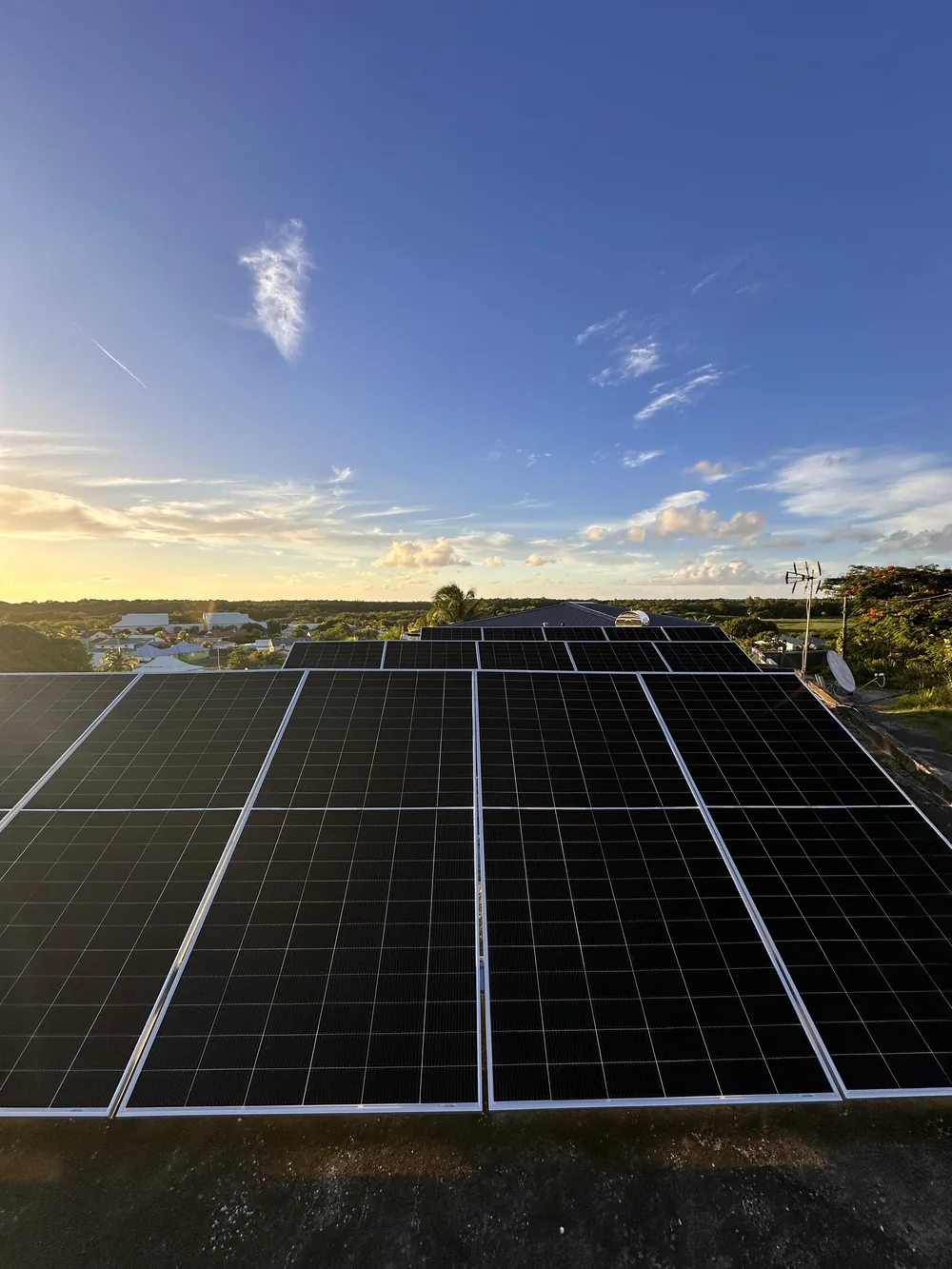 Installation solaire en toiture en Guadeloupe au coucher du soleil, panneaux photovoltaïques et vue sur la campagne